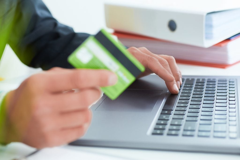Young businessman holding a credit card and typing. On-line shopping on the internet using a laptop