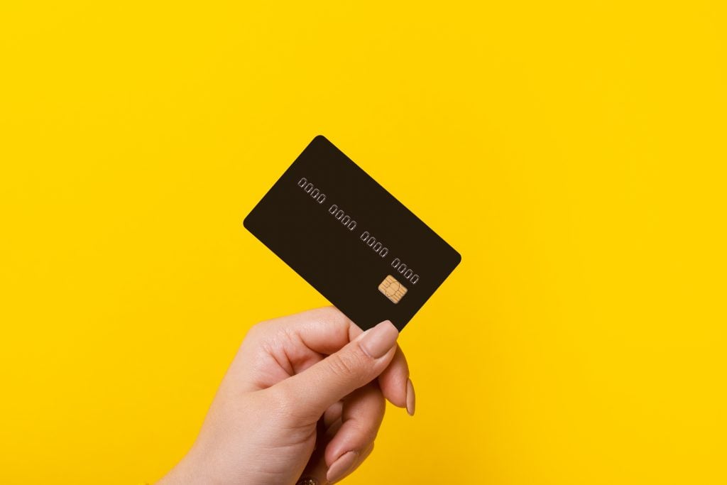 Hand holding credit card on yellow background
