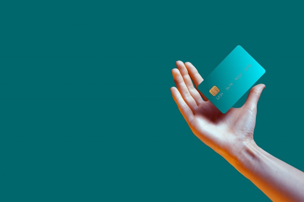 Close up female hand holds levitating template mockup Bank credit card with online service isolated on green background. High quality photo
