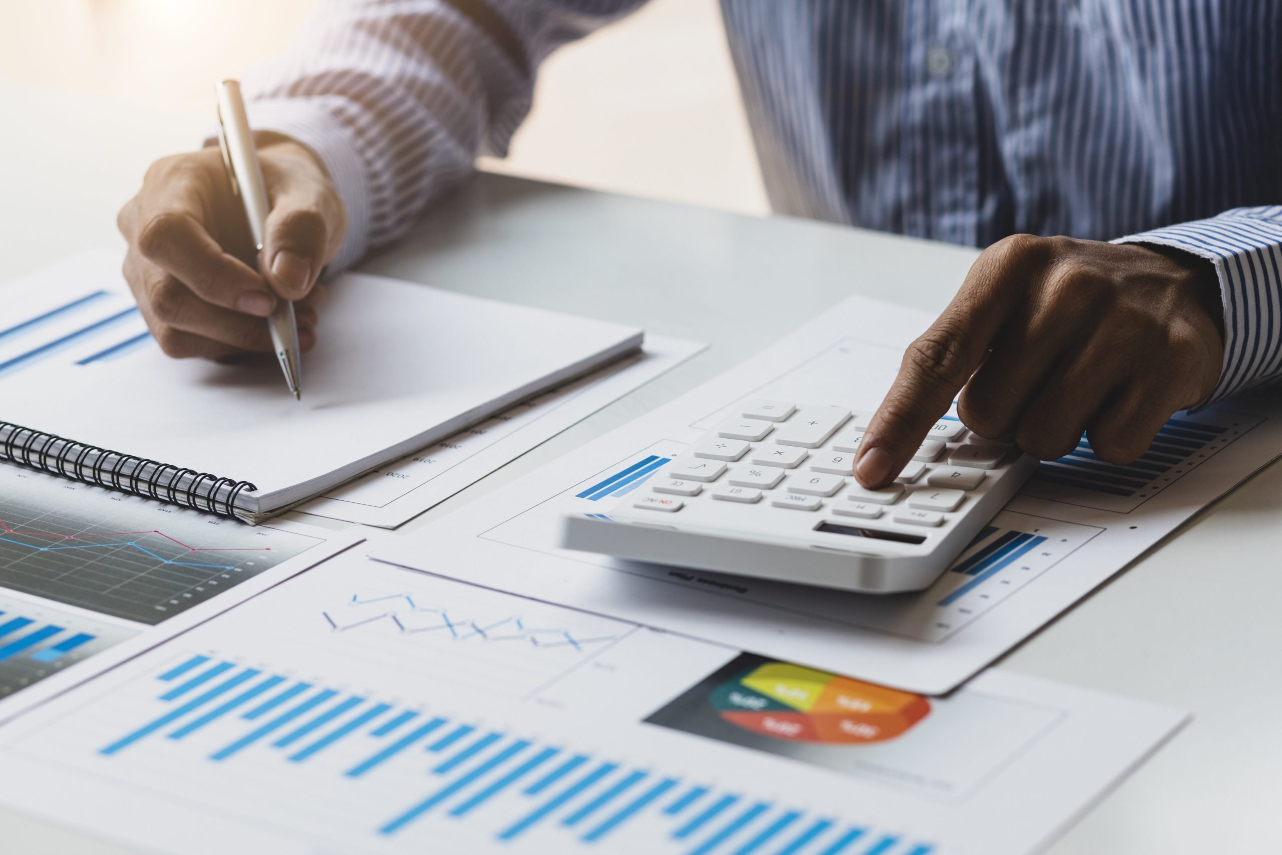 Businessman works on analyzing financial data using a calculator and writing notes with calculations