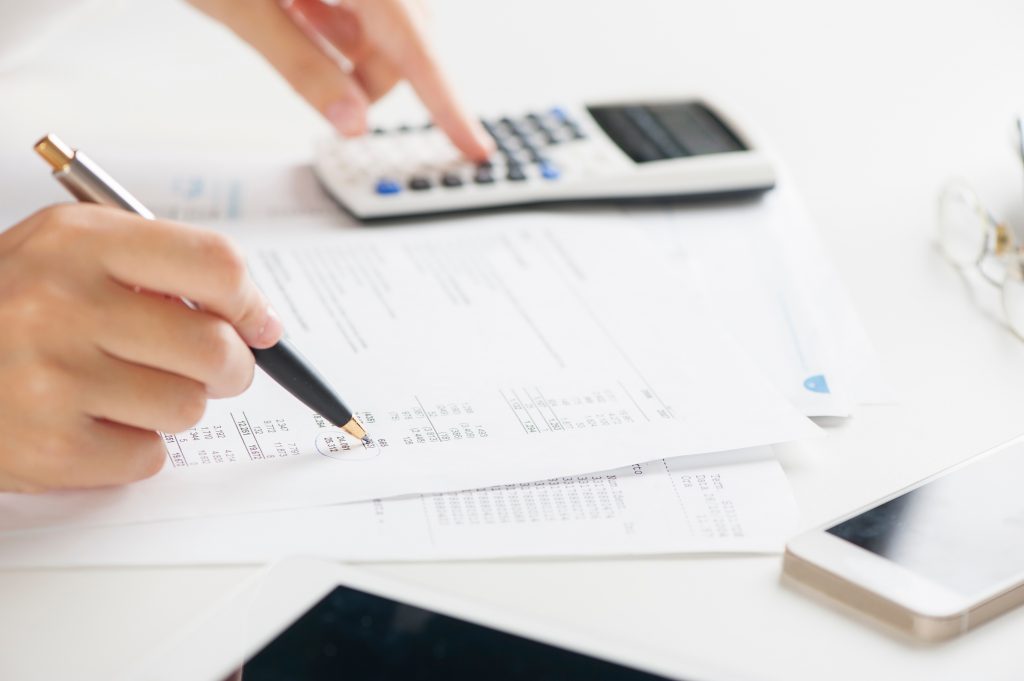 Woman writing on paper and using calculator