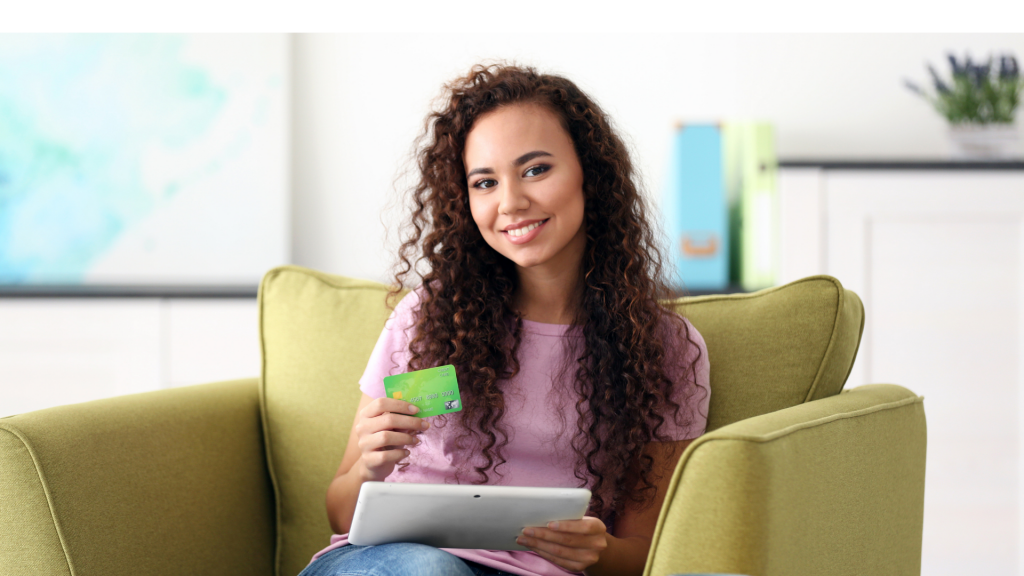 Beautiful young girl with credit card and tablet on armchair (apply upgrade card)