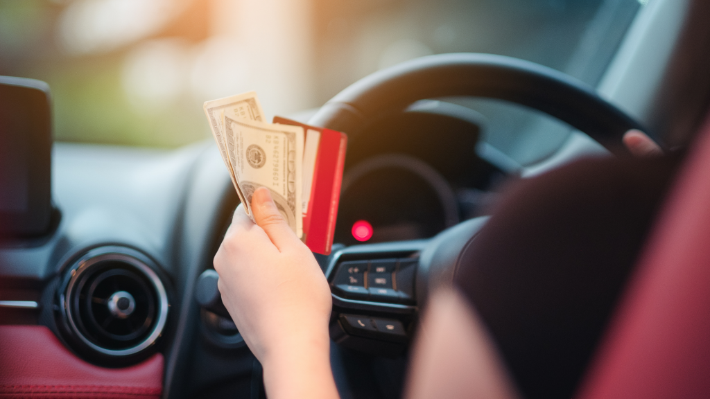 Closeup portrait hand woman sitting in her new white car showing credit card and holding dollar Personal transportation purchase concept