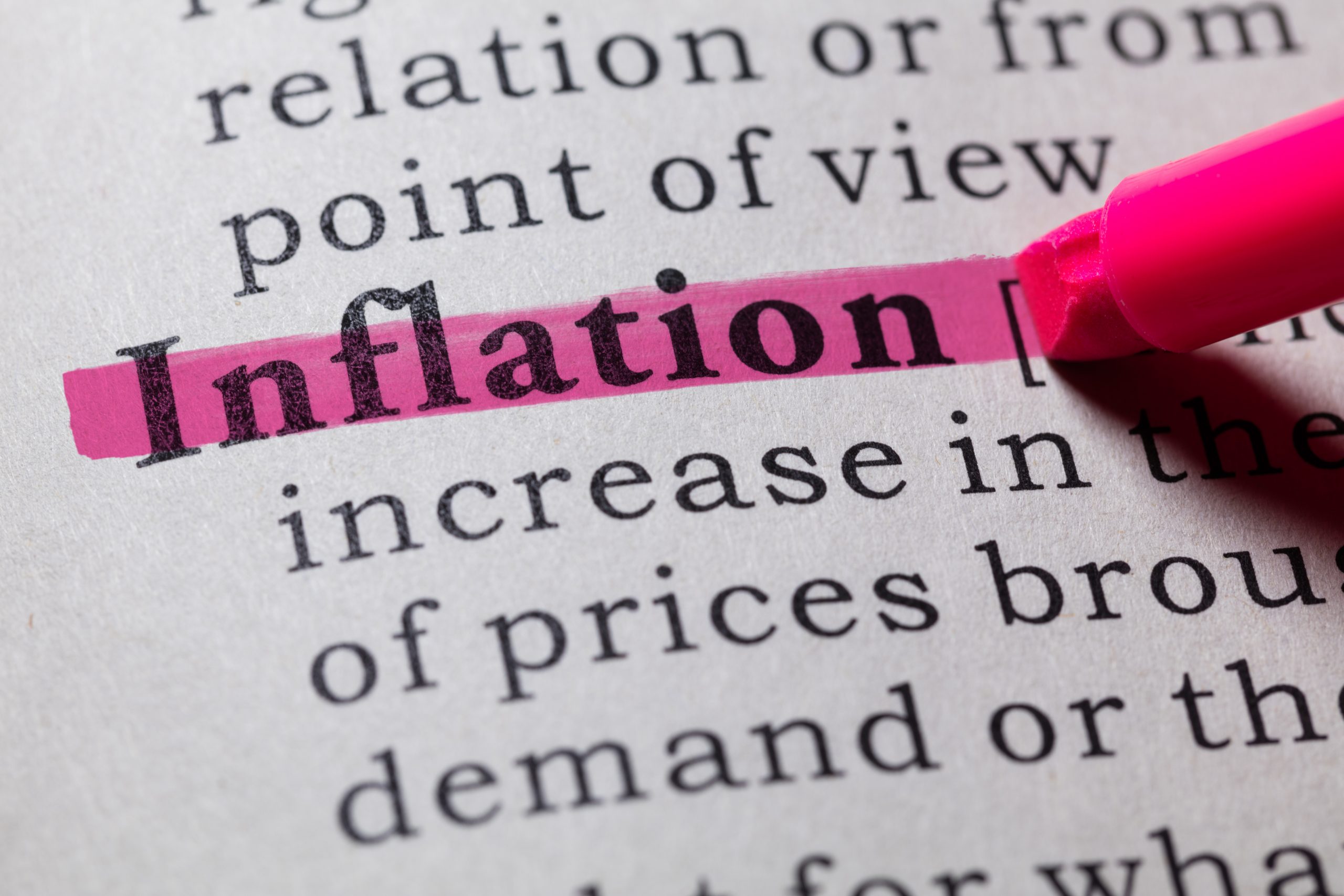 Person highlighting inflation definition on dictionary