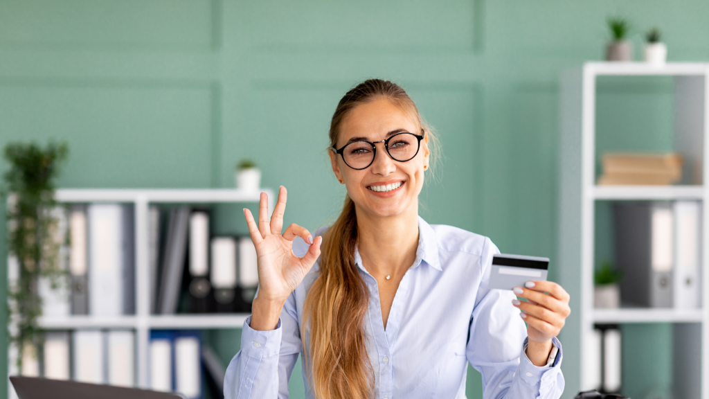 Happy woman holding credit card (apply Tangerine World Mastercard® card).