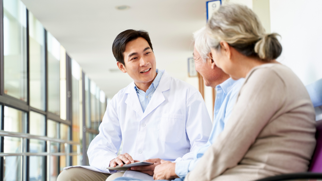 young asian doctor talking to senior couple patients in hospital hallway