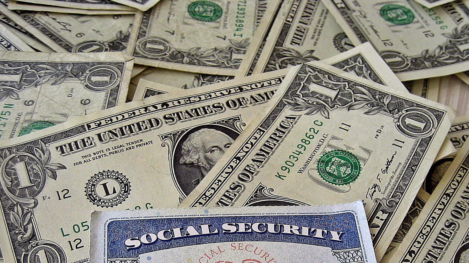 Dollars scattered on the table. At the bottom of the photo, card with the name "Social Security".