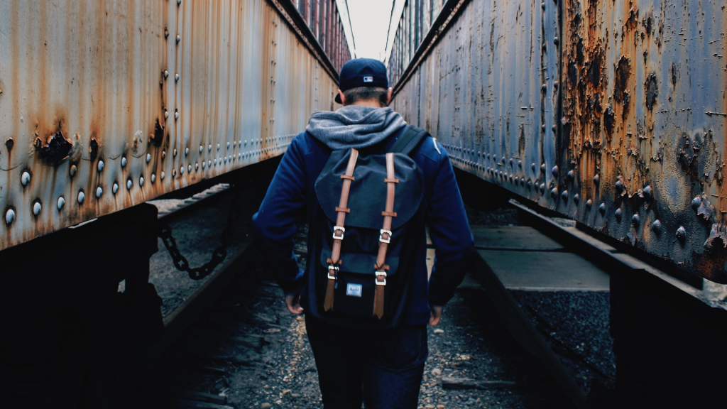 teenager from the back walking between abandoned train cars