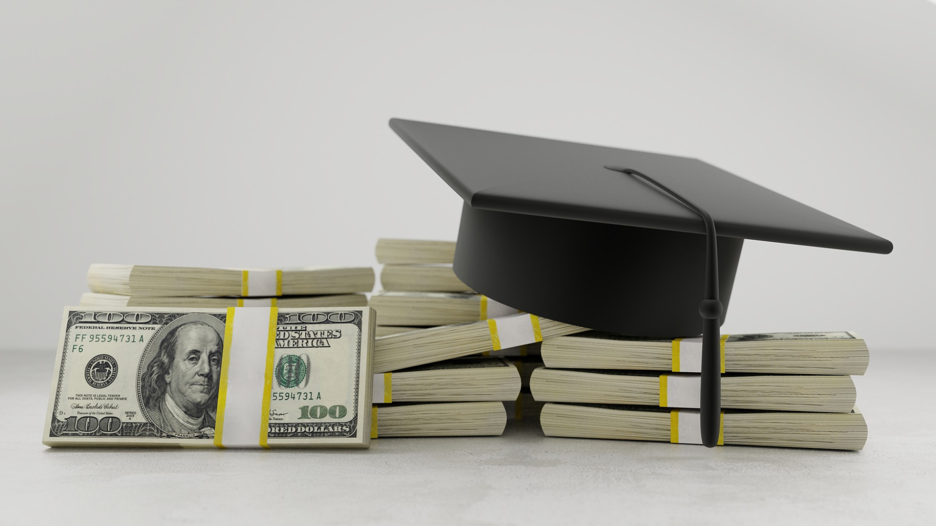 Bundles of money (dollar) bills and covered by a graduation cap (Student loan forgiveness).