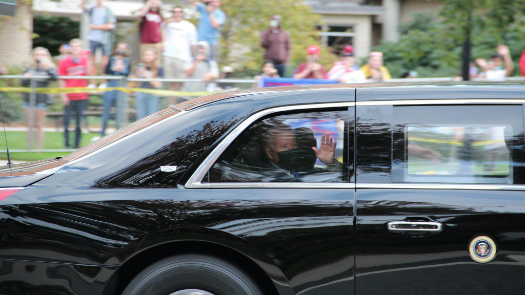 Joe Biden waving from inside the presidential car to the press.