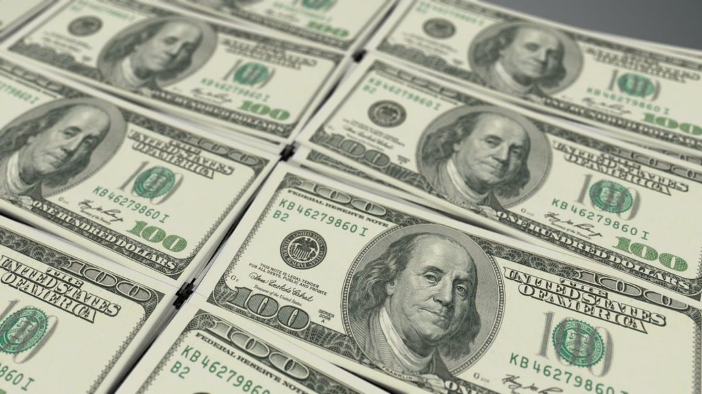 100 dollar bills arranged in small piles and laid out on a table