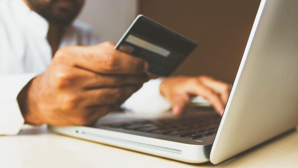 Person shopping on notebook with credit card in hand