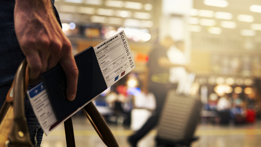 Traveler holding travel bag, passport and air ticket.
