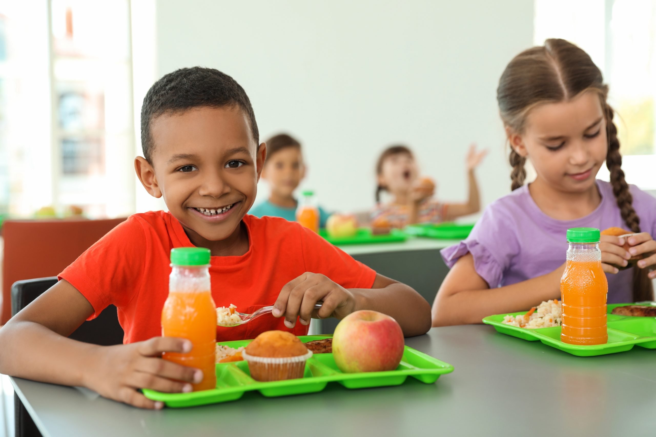 Children sitting at table and eating healthy food during break at school