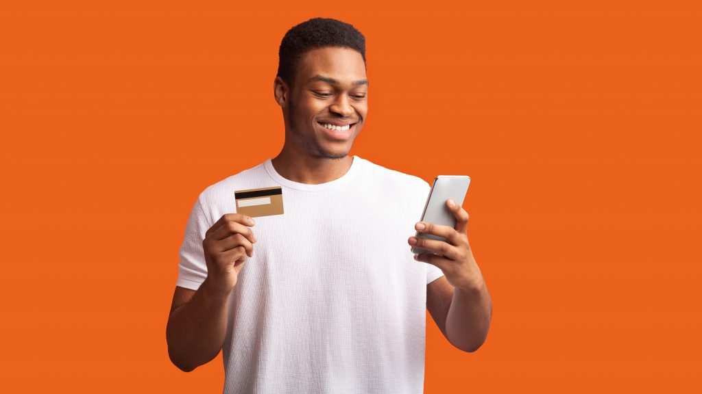 Man holding credit card and smartphone; orange background