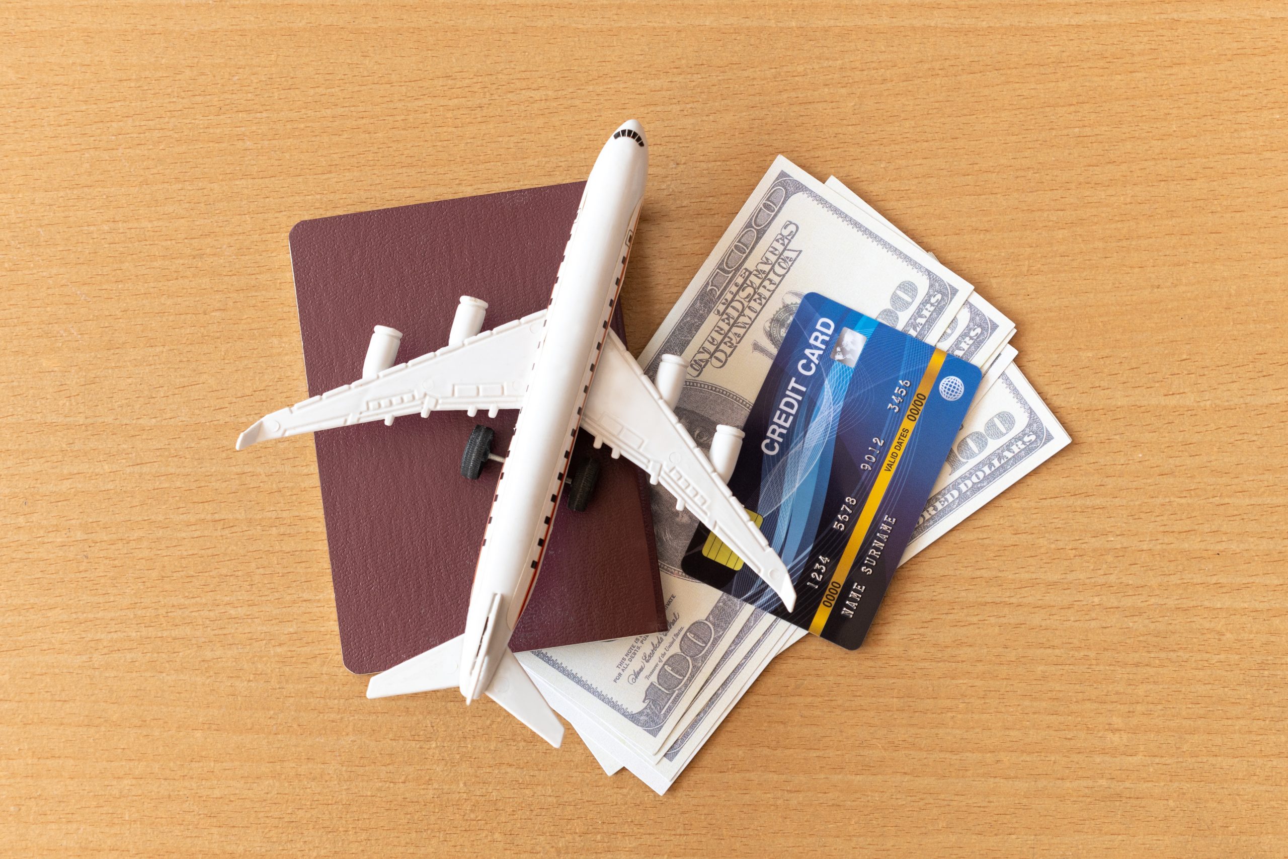 Toy airplane, credit cards, dollars and passport on wooden table. Travel concept