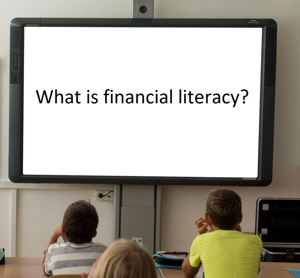 students in a classroom with the phrase "What is financial literacy" written on the board