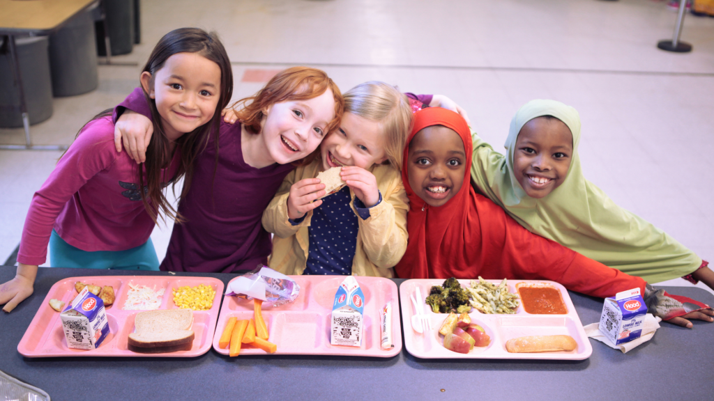 White and black children at the table eating a school meal