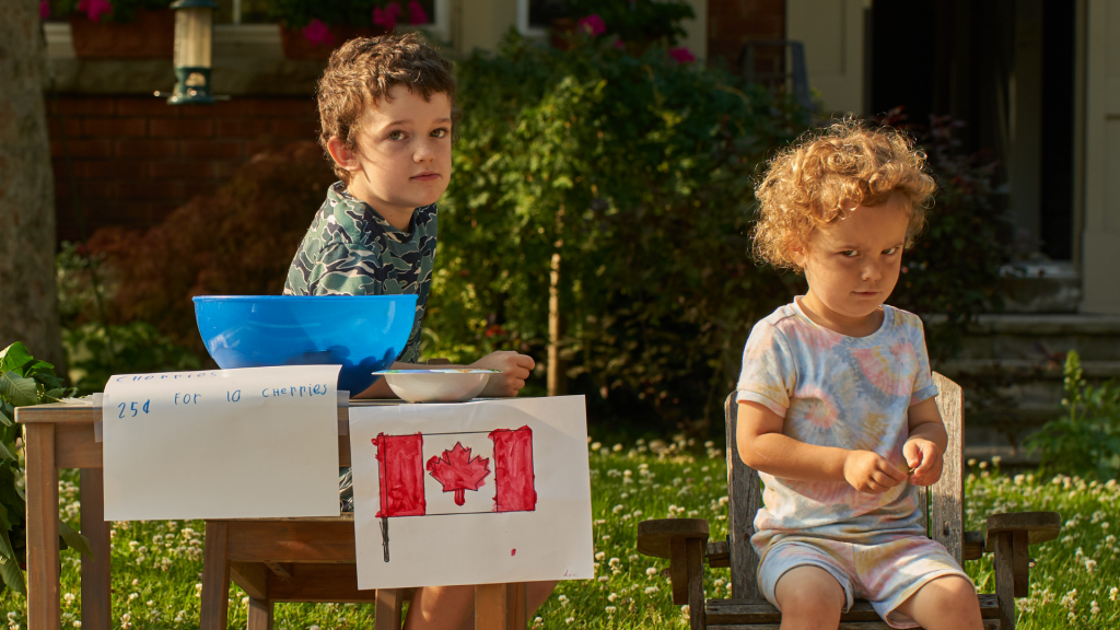 Children selling at a street stall with the flag of Canada (Inflation rate in Canada)