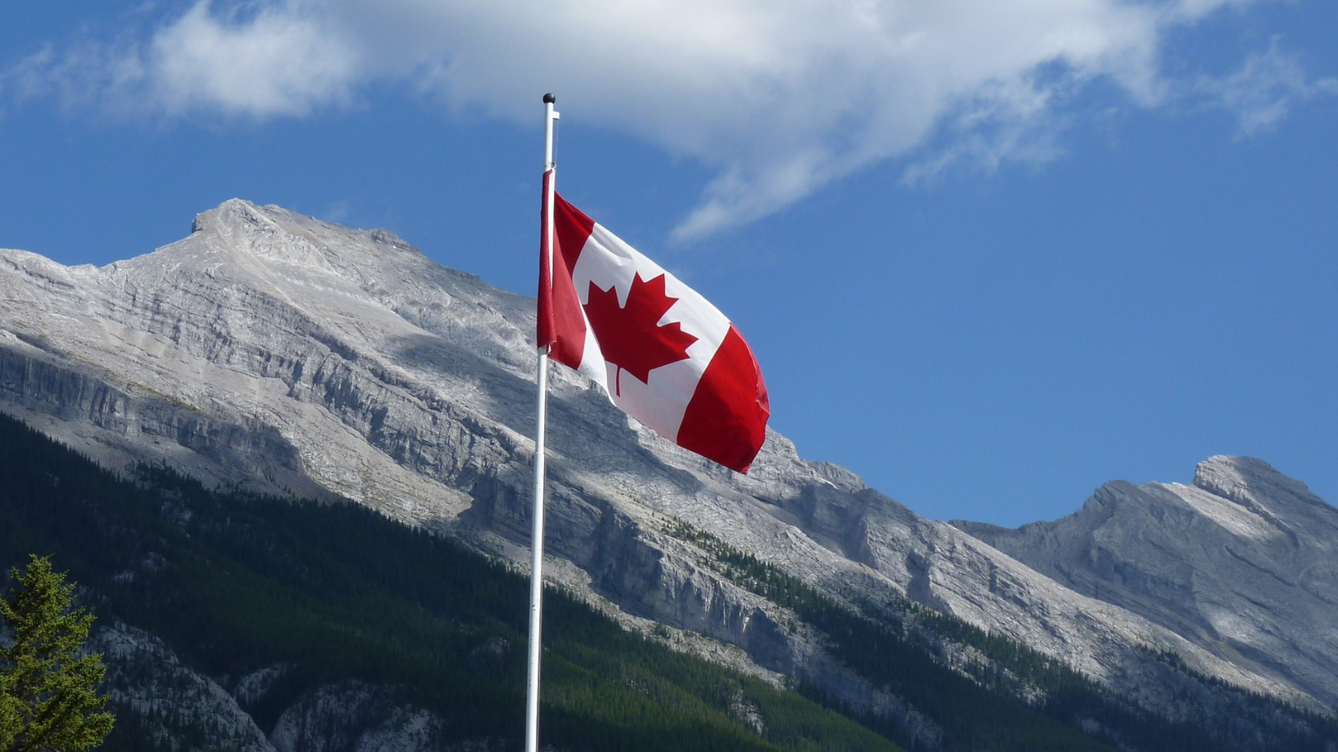 canada flag flying in the middle of the mountains