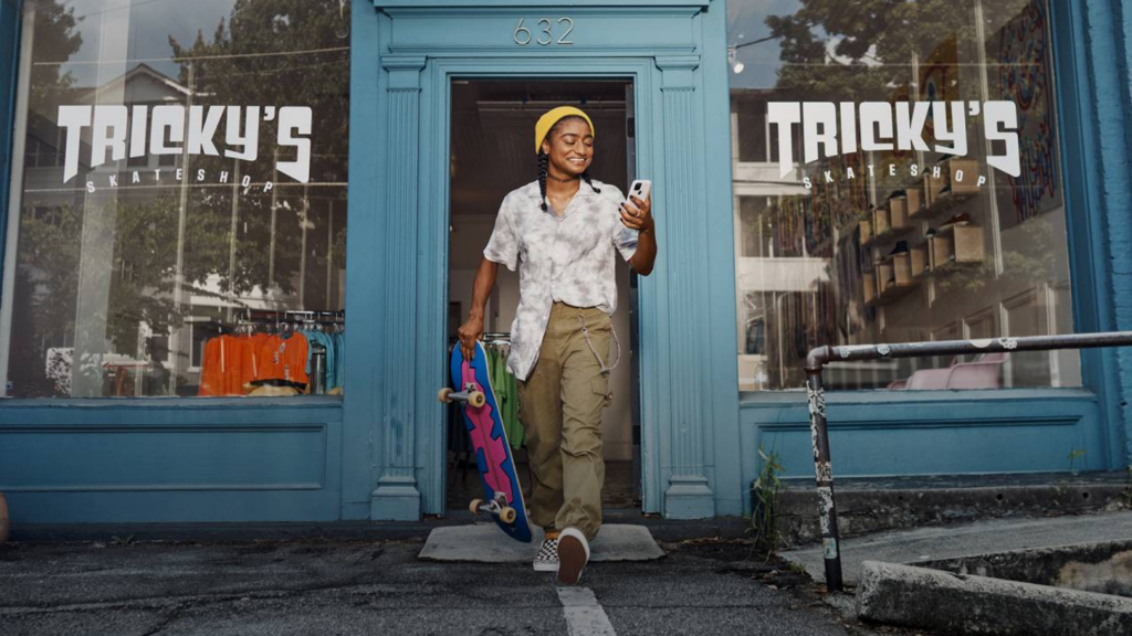 Young man with a skateboard in his hand and holding a cellphone (apply Chase Freedom® Student card)