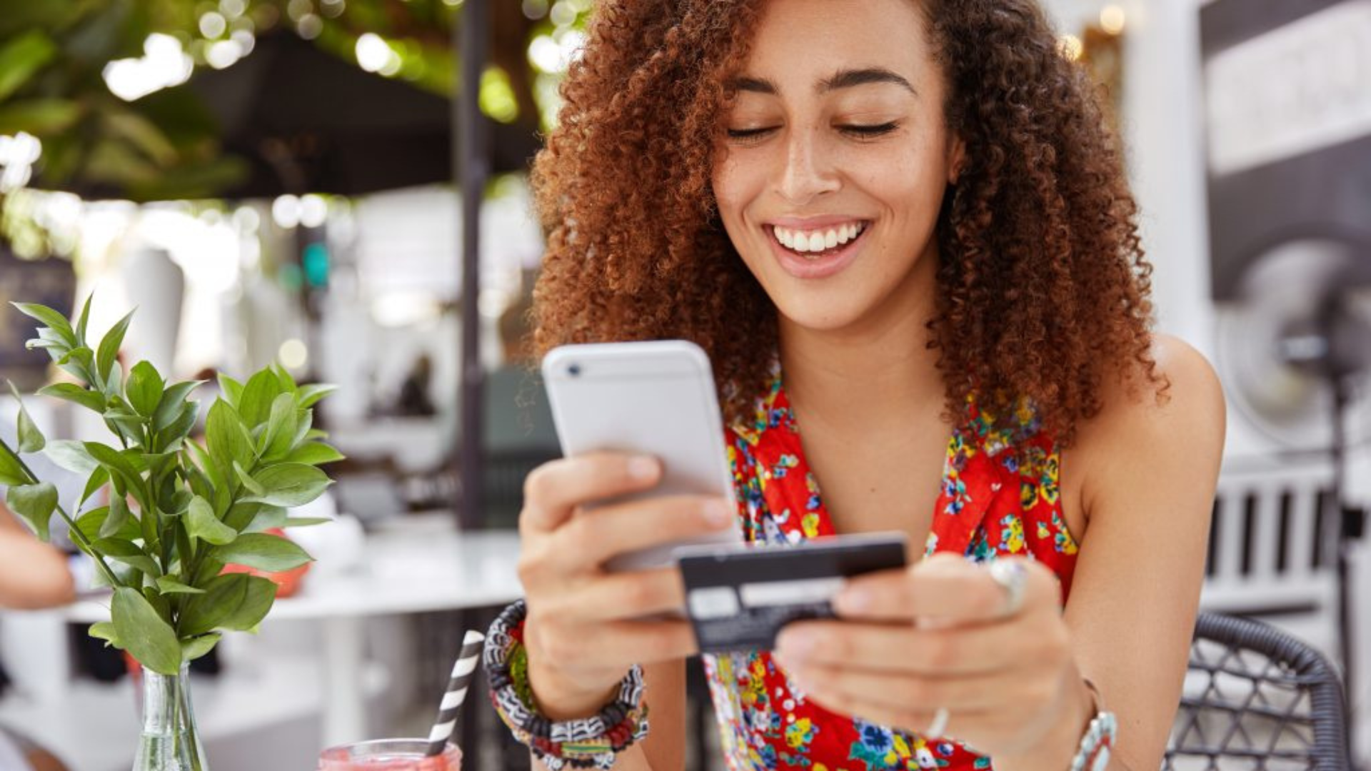 woman with curly hair using card with a smartphone in her hand