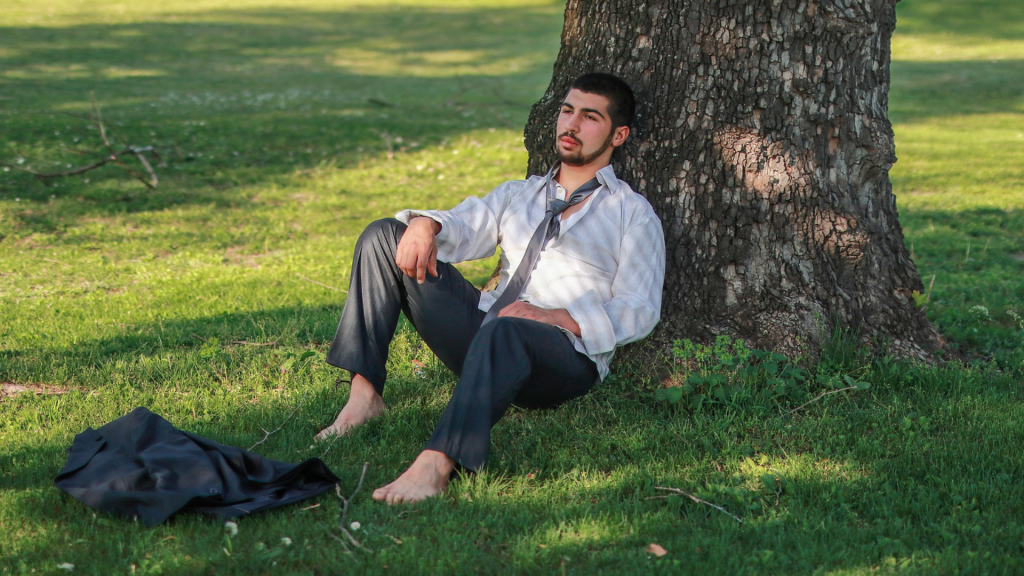 Sad, worried, angry man sitting on the grass