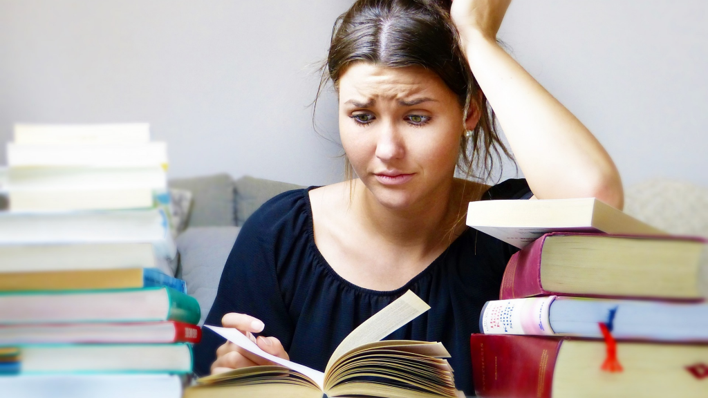 Woman around a pile of books confused (Asset management vs. wealth management)