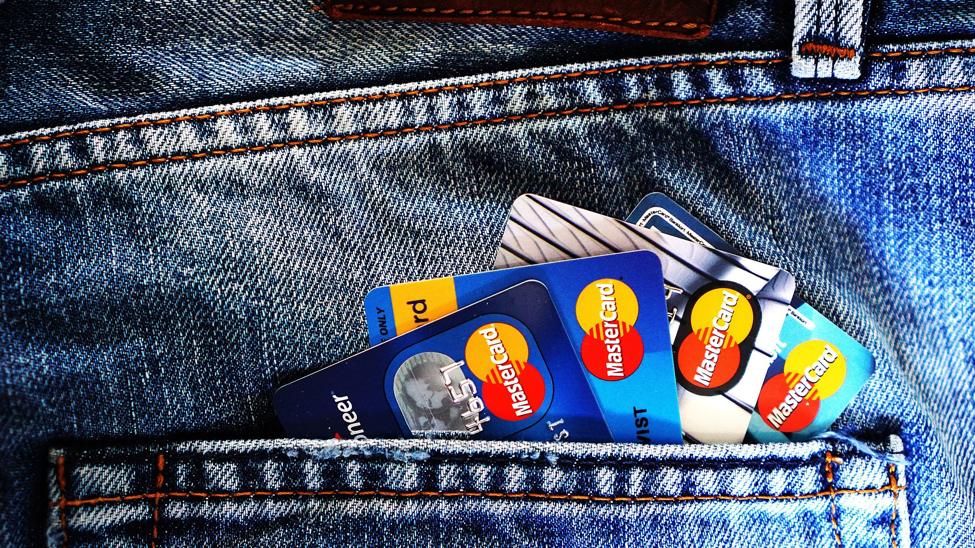 Several mastercard credit cards inside a jeans pocket (apply OakStone Platinum Secured Mastercard®)