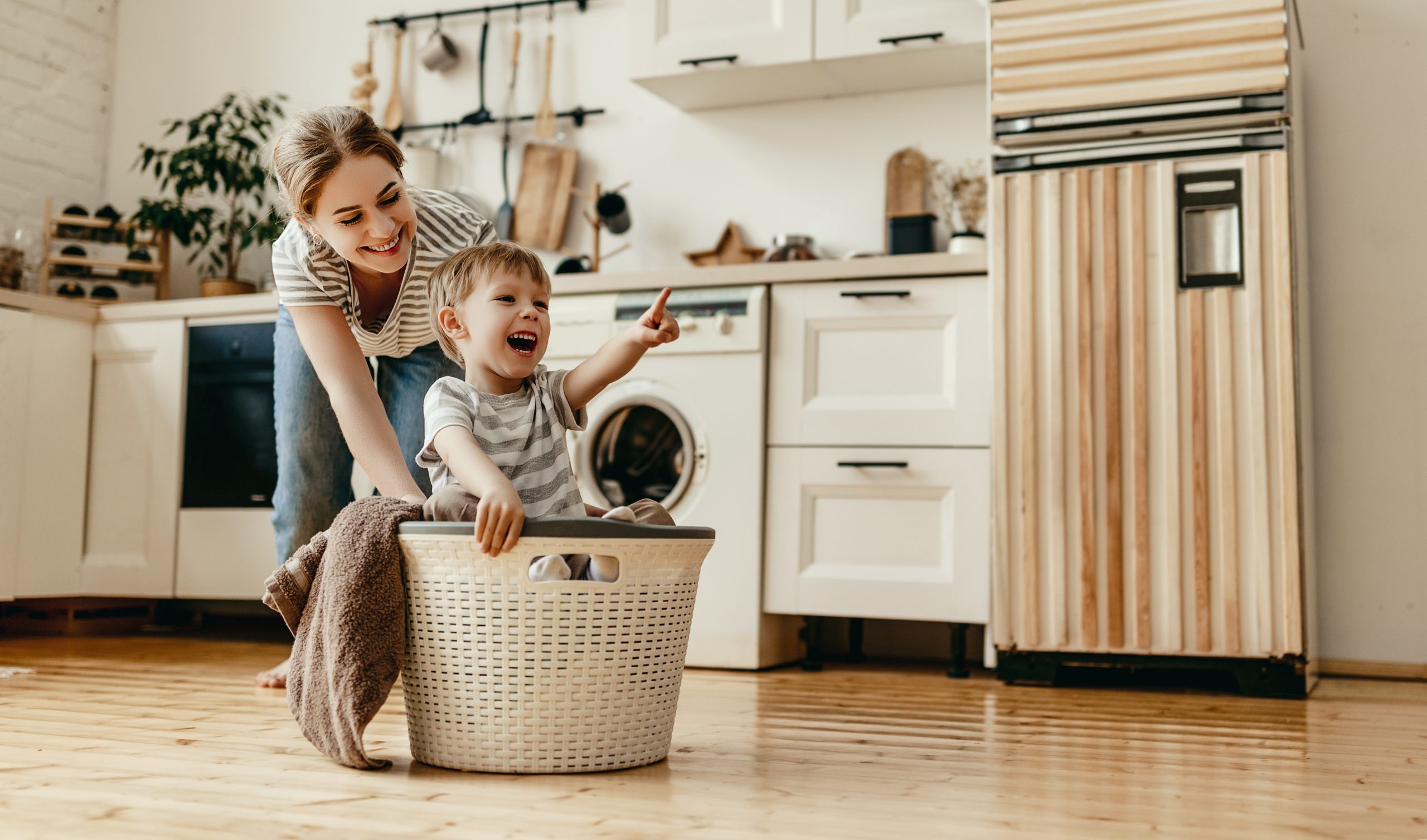 Happy family mother housewife and child in laundry with washing machine