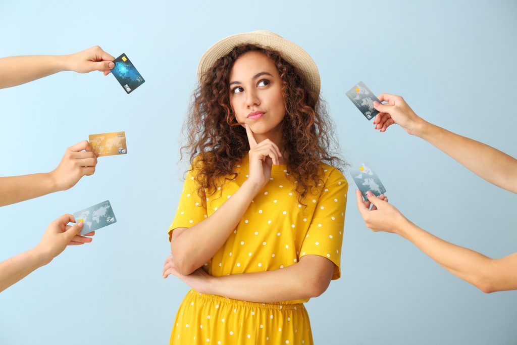 Thoughtful African-American woman and hands with credit cards on