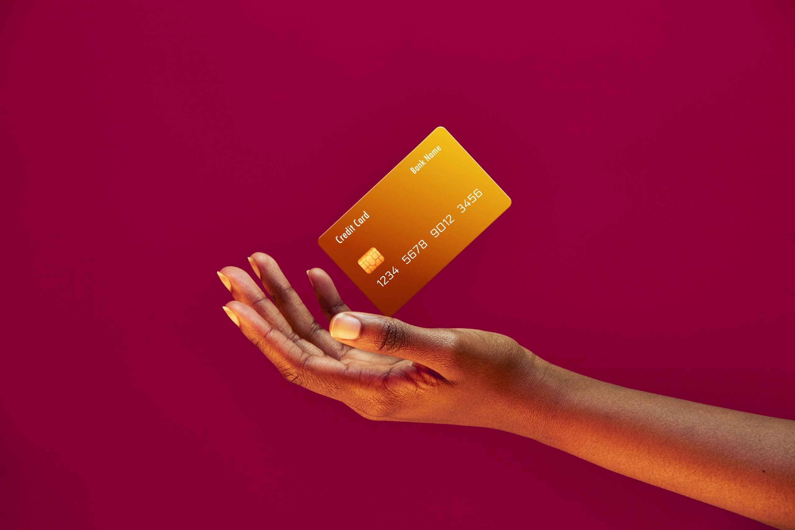 African american female hand and levitating template Bank credit card with online service on pink background