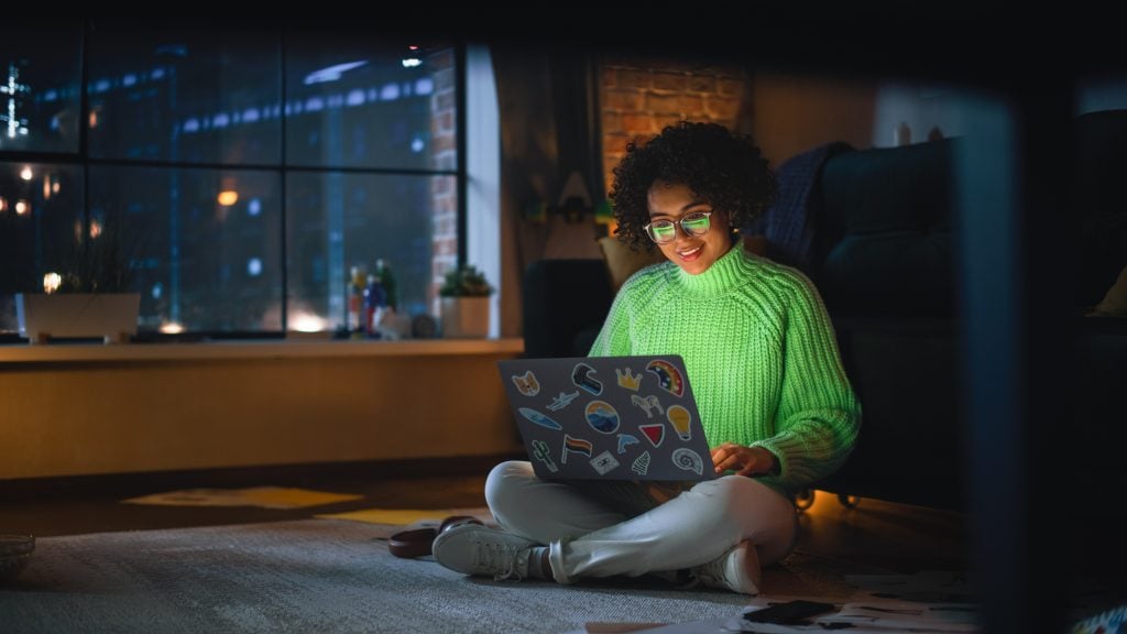 Positive Latina Female Using Laptop with Stickers at Home. Woman