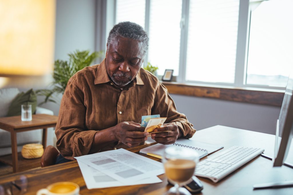 African senior man sitting at home and looking at bills he has t