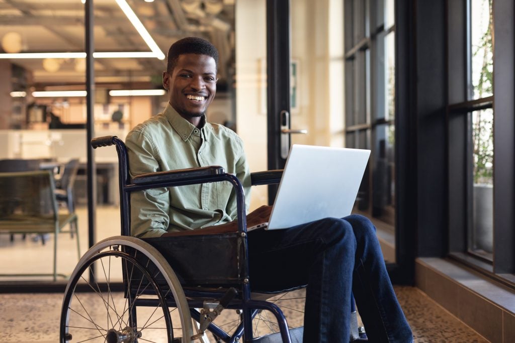 Smiling african american businessman with disability using lapto