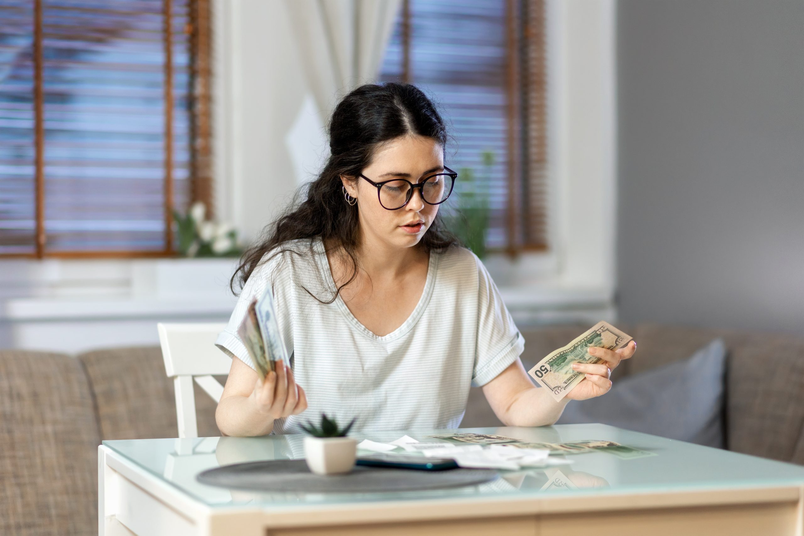 Planning of expenses. Portrait of caucasian young woman accounting cash and paper receipt. Concept of payment of utilities, tax return and savings