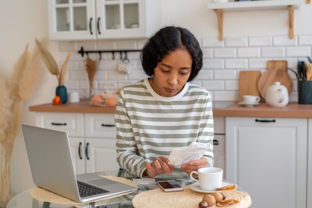 African-american female paying bills. Dealing with expenses on smartphone. Cutting back on spending