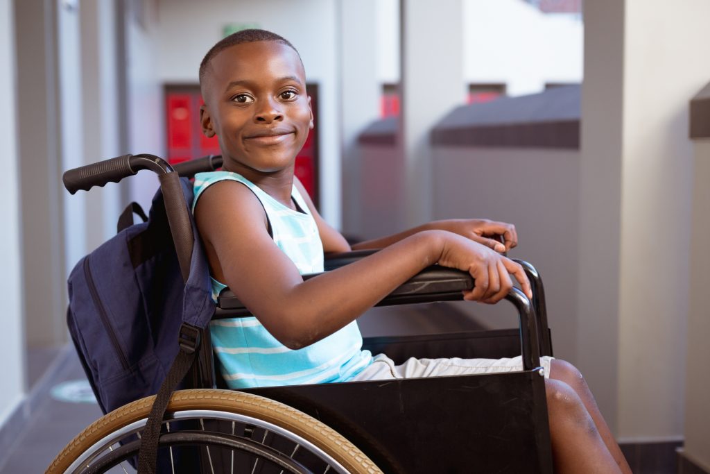Portrait of smiling disabled african american schoolboy sitting