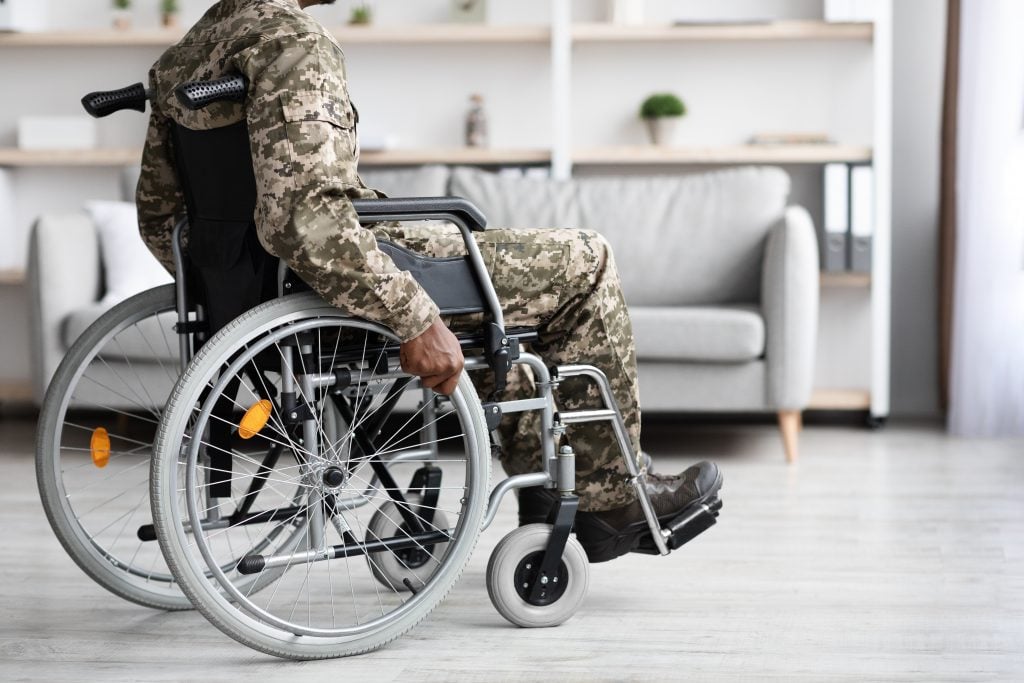 Cropped of black veteran in wheelchair rolling by home