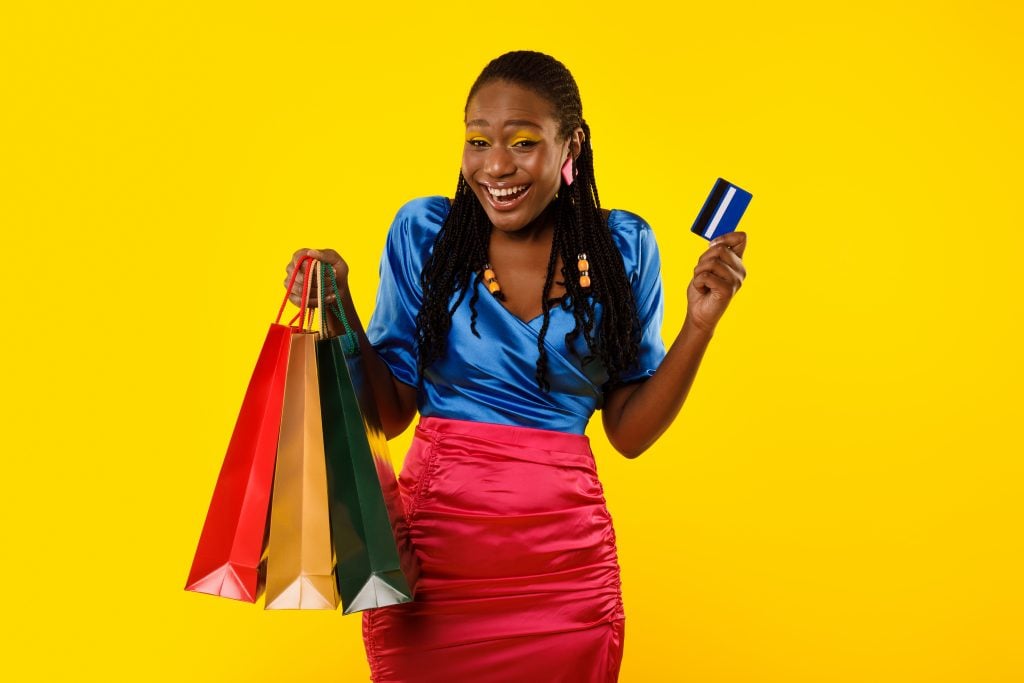 Black Woman Holding Shopping Bags And Credit Card, Yellow Background