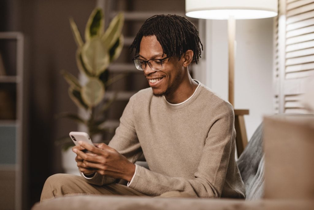 man-using-modern-smartphone-device-while-couch-home