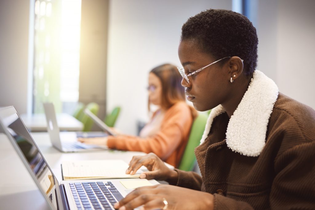 Education, black woman and laptop for studying, knowledge and learning in classroom. African American female, student and academic with online research, study notes or prepare for exam, test or focus