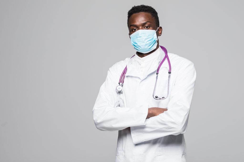 African-American medical doctor man with mask isolated on gray b