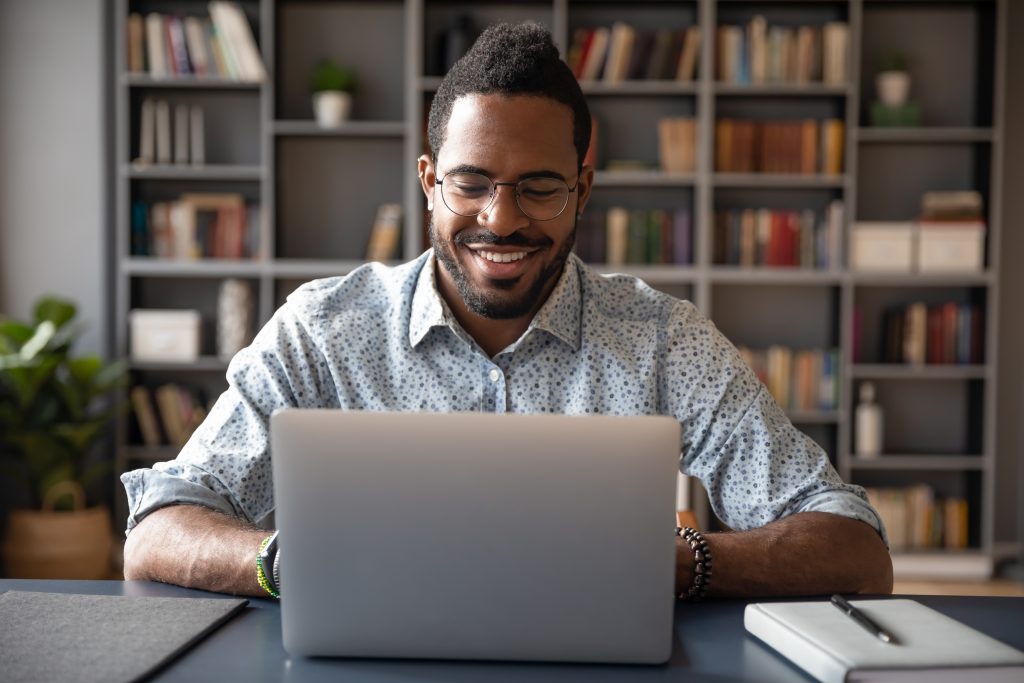 Young smiling african american businessman looking at laptop screen.