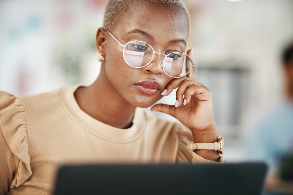 Office, laptop and black woman, serious and reading email or online research report, with glasses. Computer, concentration and African journalist proofreading article on digital news website or blog