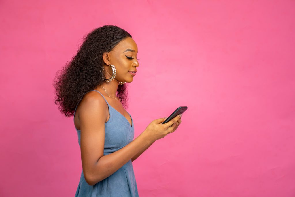 beautiful young african woman using her mobile phone and credit