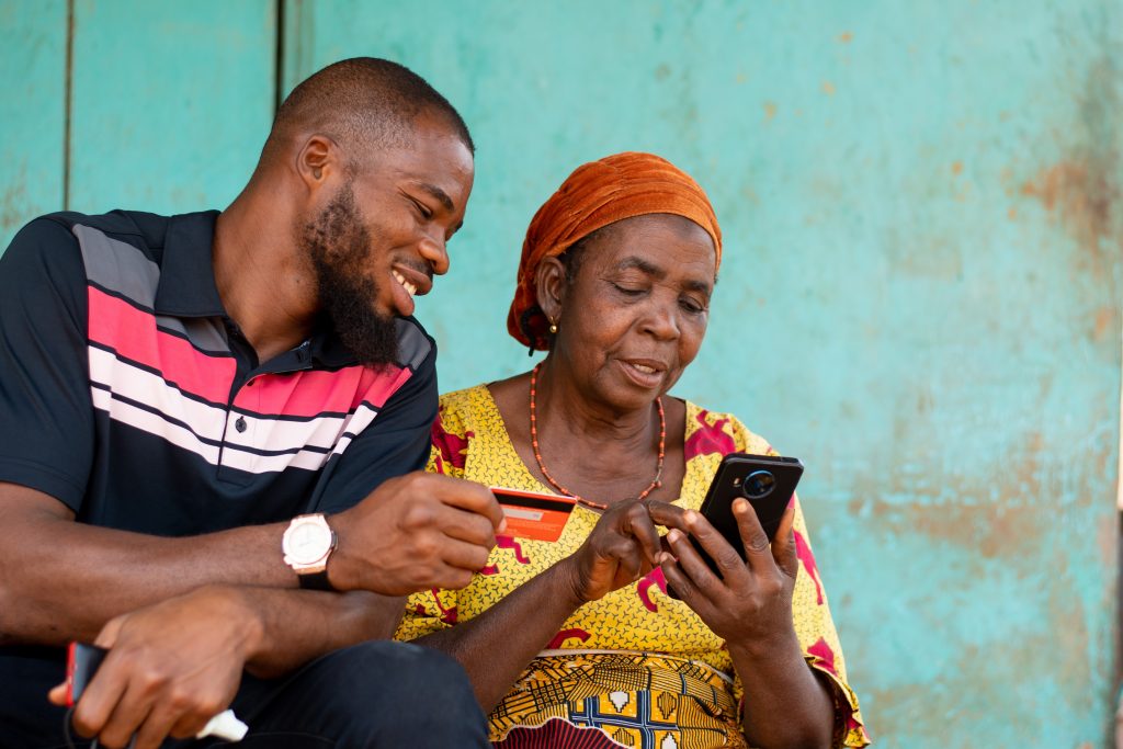 elderly african woman and young man use phone and credit card