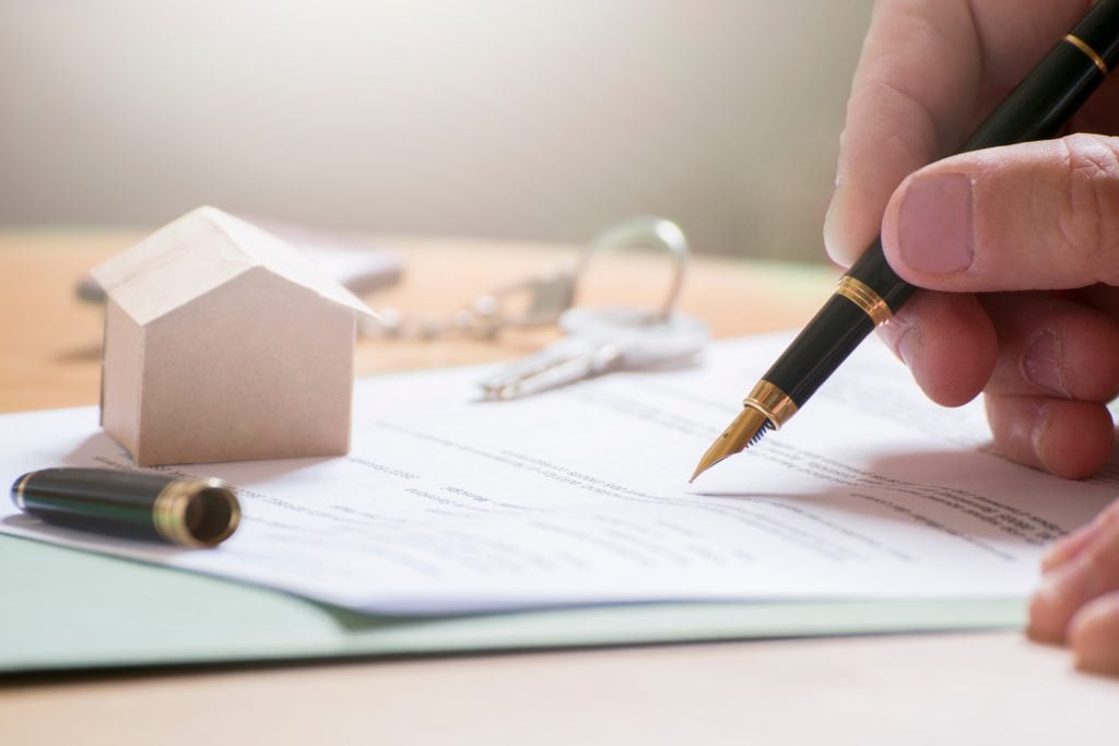 Man hand signing documentation for home mortgage with a pen. Key